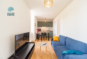 A modern living room with a TV, sofa, and coffee table, leading to a kitchen with a dining area. - Cozy & centrally located apartment in Guingamp (Guingamp)