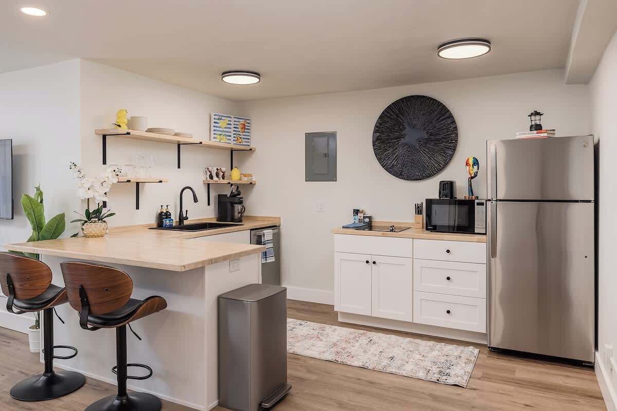 A modern kitchen with a central island, white cabinetry, a stainless steel refrigerator, and a microwave.