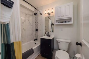 A bathroom with a bathtub, toilet, sink, and a cabinet with a mirror.