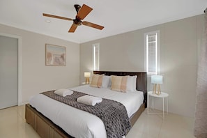 A hotel room with a large bed, a ceiling fan, two bedside lamps, and a framed picture on the wall.