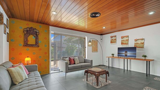 A living room with a sofa, a coffee table, a TV on a stand, and a wooden ceiling. - Sunrise on Sovereign - Retro Family Entertainer (Dubbo)