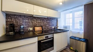 Una cocina moderna con salpicadero negro, electrodomésticos de acero inoxidable y un ventanal que proporciona luz natural.