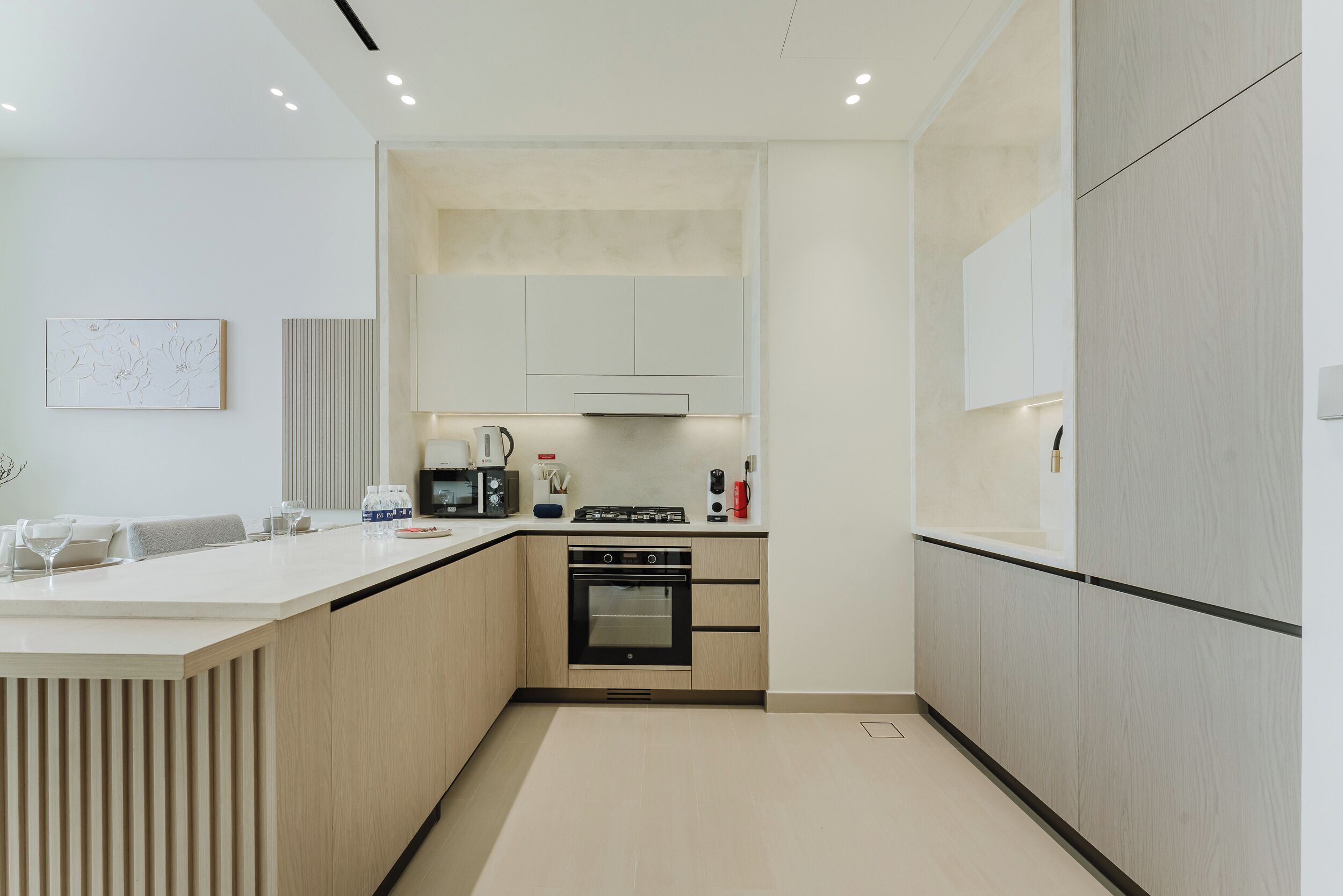 A modern kitchen with a central island, built-in oven, and white cabinetry.