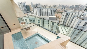 A rooftop pool with a glass balustrade, a seating area, and a cityscape view. - PVH - Lavish 1BR - Private Pool (Dubai)