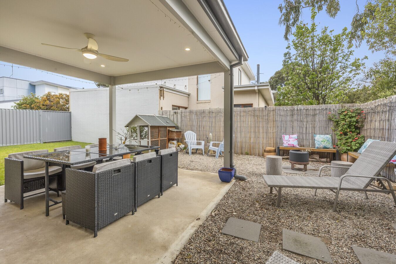 An outdoor patio with a table and chairs, a small playhouse, and a wooden fence.
