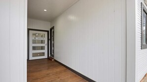 Un passadís amb parets blanques i terra de fusta, que condueix a una porta amb la inscripció 'HOTEL ENTRY'.