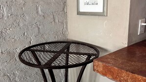 Een hoekzaal met een structuurwand, een ingelijst kunstwerk, een ronde metalen tafel en een bruin aanrecht.