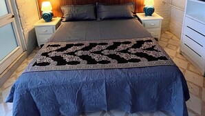 Een slaapkamer met een bed, twee bedlampen, een plafondventilator en een airconditioning.