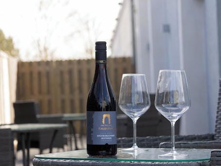 A bottle of wine and two glasses on a glass table outdoors.. Fairschlafen Boutique Hotel