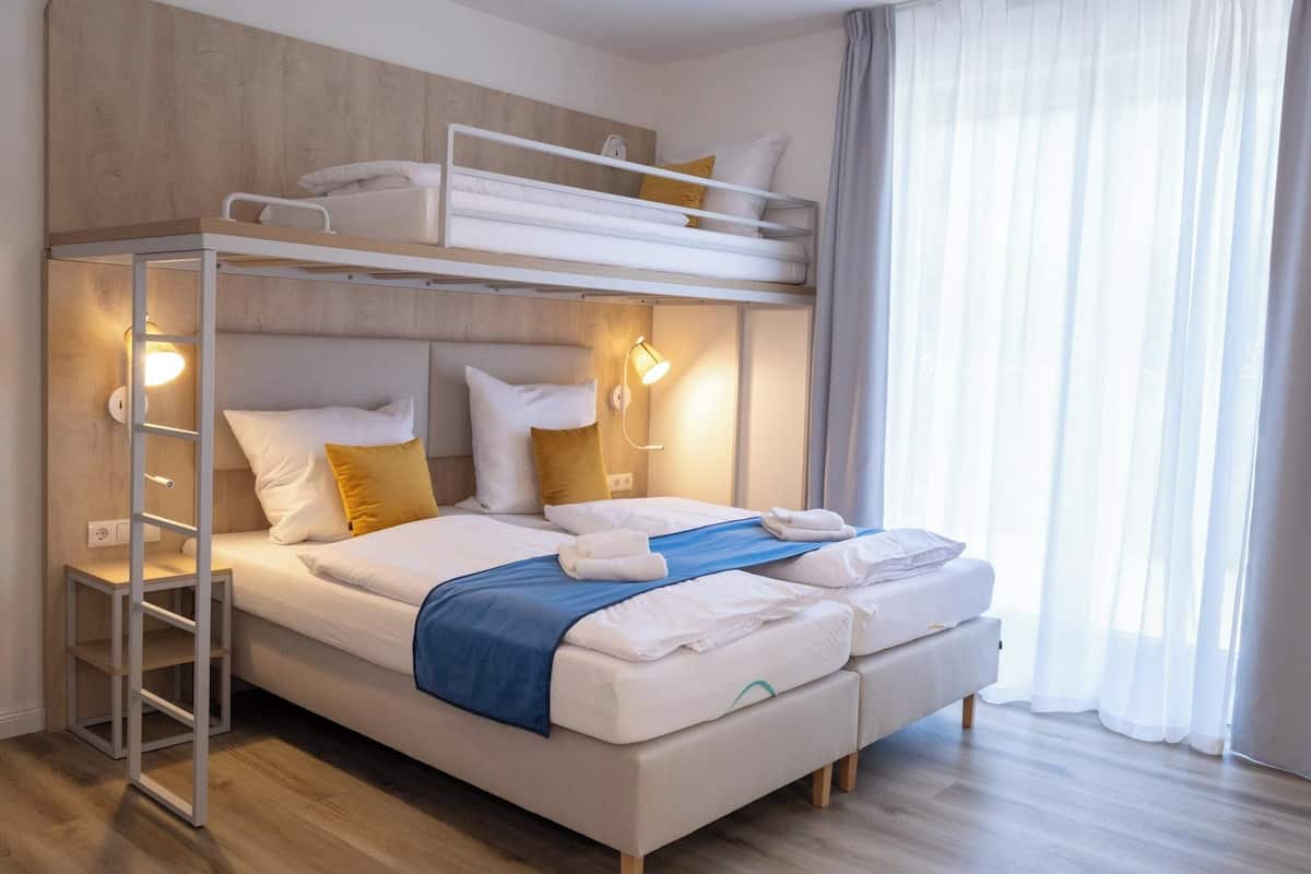 A bunk bed with a ladder, bedside lamps, and a blue blanket.