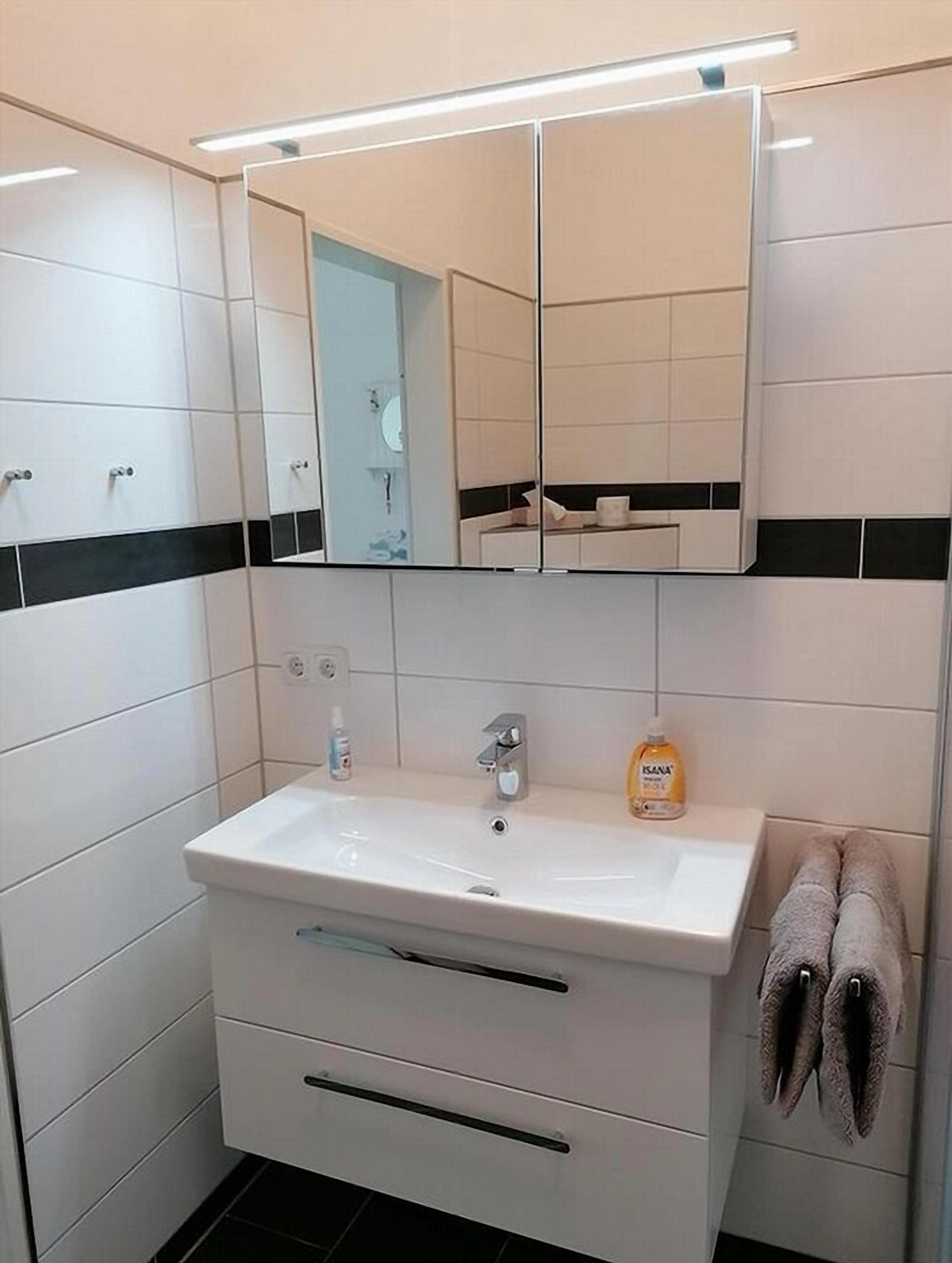 Une salle de bain avec un lavabo blanc, un miroir et un porte-serviettes.