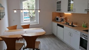Una cocina moderna con armarios blancos, una mesa de comedor con sillas, un ventanal con vistas y un horno empotrado.