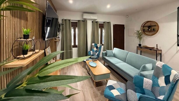 Een moderne woonkamer met een bank, een salontafel, een televisie en een wandplank met planten.