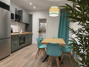 A modern kitchen with grey cabinets, a microwave, and a stove. There is a dining table with four chairs. - Huelin Beach House: Solarium 200 m from the Sea (Malaga)