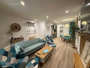 Een moderne woonkamer met een bank, fauteuils, een salontafel en een eethoek met stoelen en een tafel.