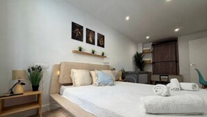Een moderne slaapkamer met een groot bed, nachtkastjes, een bureau en een raam met gordijnen.