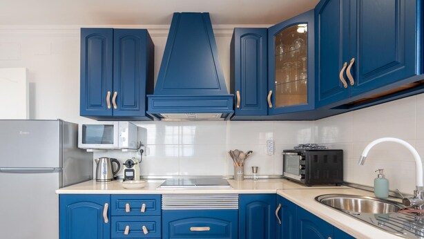 A modern kitchen with blue cabinets, a stainless steel refrigerator, a microwave, a kettle, a toaster, and a sink with a faucet. - Vivelorural Casa Marao Great sea Views (Arucas)
