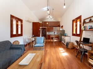 A modern living room with a sofa, a coffee table, and a dining area with chairs and a table. - Vivelorural El Olivo de Ayagaures (San Bartolomé de Tirajana)