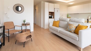 A modern living room with a sofa, chairs, a small table, and a kitchen area in the background. - Vivelorural Agaete Great Garden (Agaete)