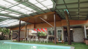 A pool area with a covered roof, lounge chairs, and a bar area. - Le Ping Villas (Kao Liao)