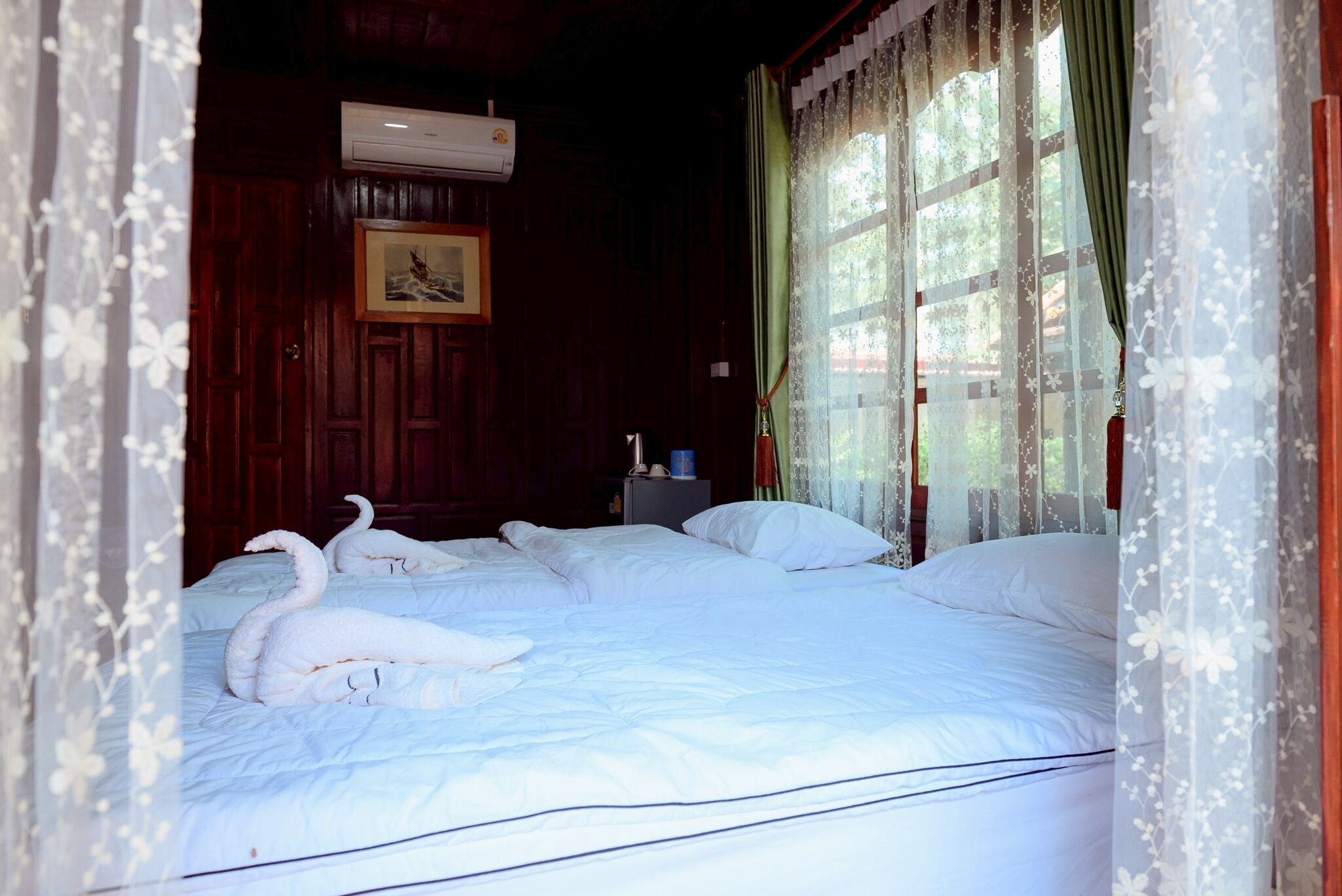 A room with a bed, a picture on the wall, and a window with curtains.