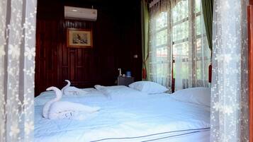 A room with a bed, a picture on the wall, and a window with curtains.