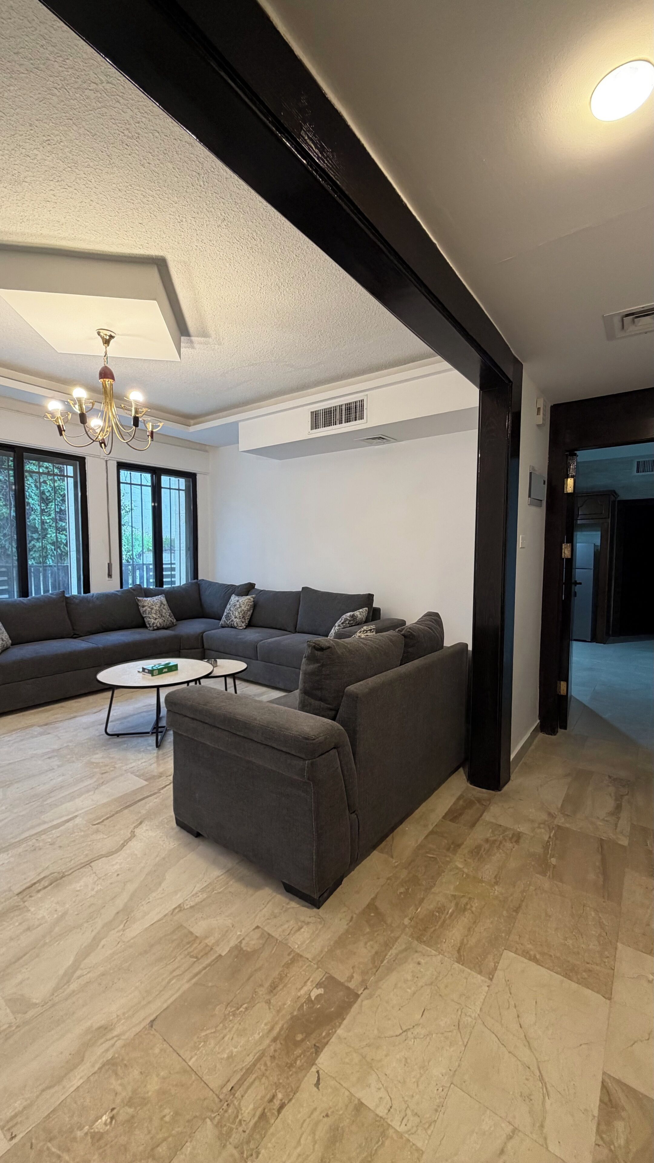 A modern living room with a sectional sofa, a small coffee table, and a chandelier.