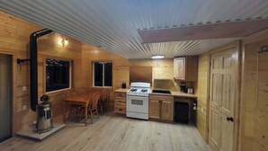 A compact wooden cabin with a dining area, kitchen, and a single door.