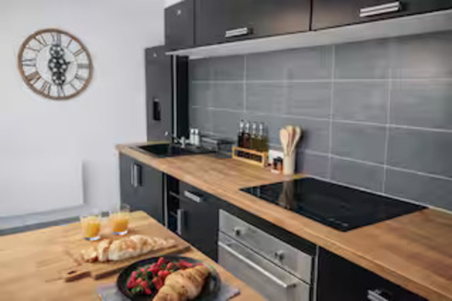 Una cocina moderna con encimera de madera, electrodomésticos de acero inoxidable y un reloj en la pared.