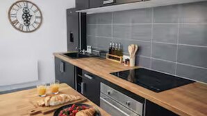 Une cuisine moderne avec un plan de travail en bois, des appareils électroménagers en acier inoxydable et une horloge au mur.