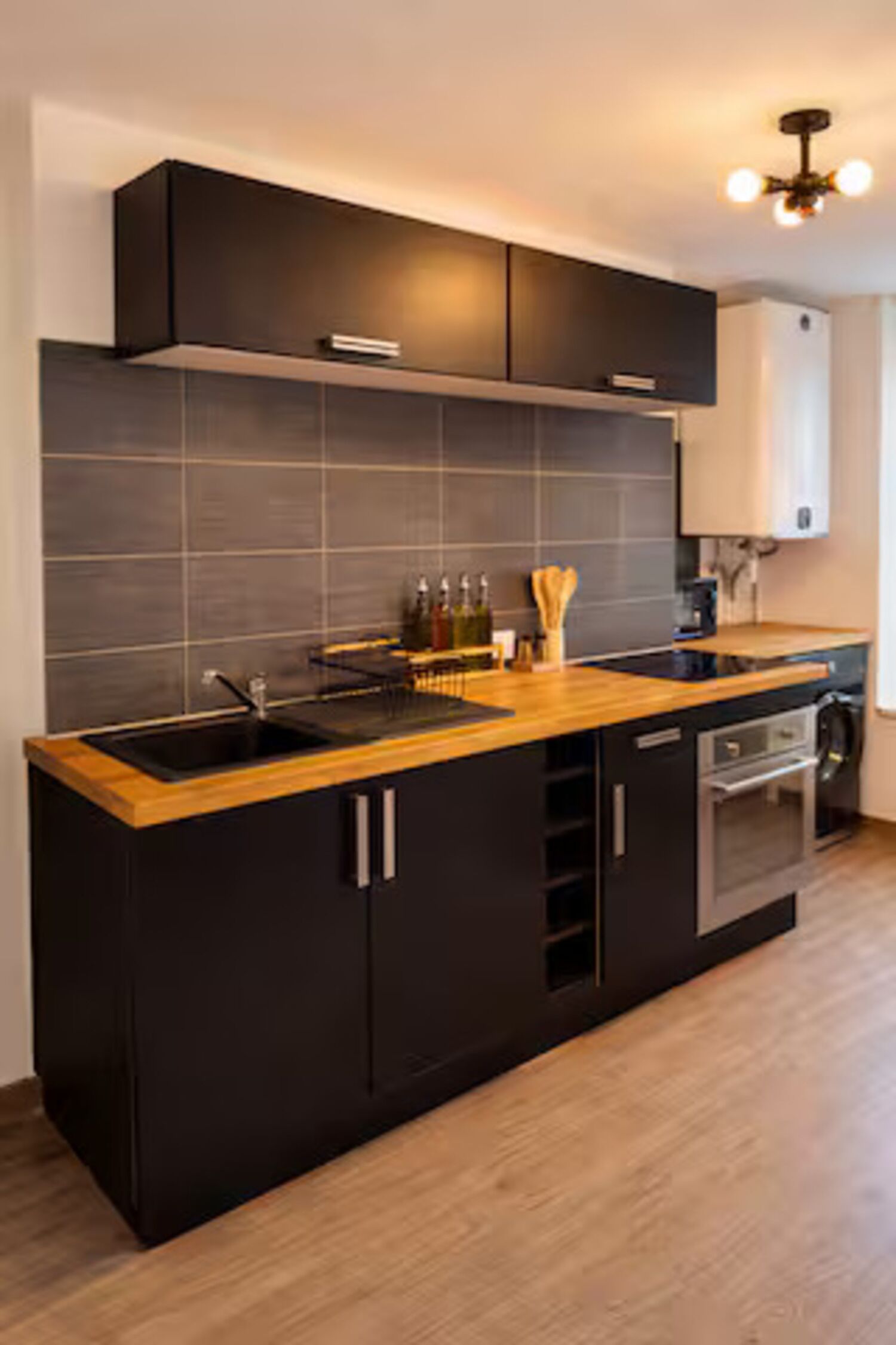 Una cocina moderna con armarios oscuros, encimera de madera y horno empotrado.