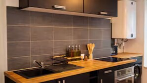 Une cuisine moderne avec des meubles de couleur sombre, un plan de travail en bois et un four encastré.