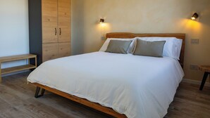 Ein Schlafzimmer mit einem hölzernen Bett, zwei Nachttischlampen, einem Holzschrank und einer Bank.