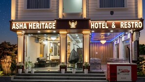 A hotel entrance with a sign reading 'ASHA HERITAGE HOTEL & RESTRO,' a reception area with a chandelier, and outdoor seating. - Asha heritage Hotel & Restro (Haridwar)