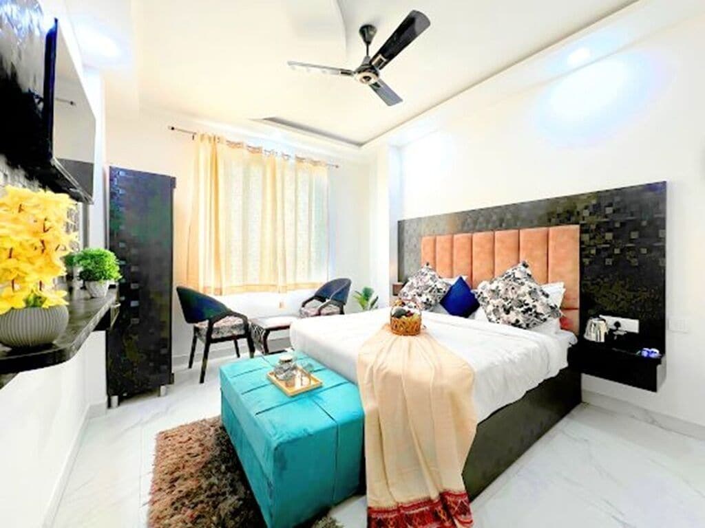A modern hotel room with a bed, a desk, a chair, a ceiling fan, and a window with curtains.