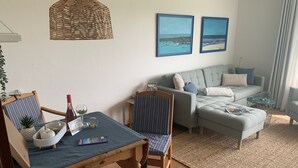 En stue med et spisebord, stole, en sofa og to billeder hængende på væggen.