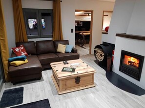 A living room with a sofa, a wooden coffee table, a fireplace, and a television. - At the Chalet de Mélines (EREZEE)