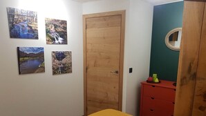 Makuuhuone, jossa on sänky, puinen ovi, lipasto ja neljä maisemakuvaa seinällä.