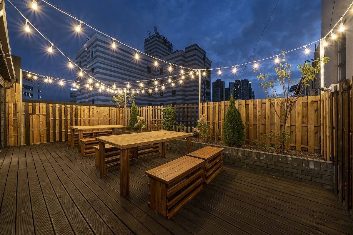Eine Terrasse im Freien mit Holzmöbeln und Lichterketten.