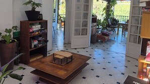 Um quarto espaçoso com teto alto, mesa de centro de madeira, estante de livros e um vaso com planta.