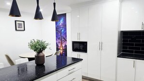 A modern kitchen with white cabinets, a black countertop, and pendant lighting. - Tranquil Oakhurst Retreat Your Peaceful Home Away from Home (Oakhurst)