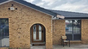 A brick building with a large arched entrance, a window with a metal grill, and a small outdoor seating area. - Tranquil Oakhurst Retreat Your Peaceful Home Away from Home (Oakhurst)