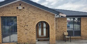 Un bâtiment en briques doté d’une grande entrée en arc de cercle, d’une fenêtre avec une grille métallique et d’un petit espace extérieur aménagé en coin salon.