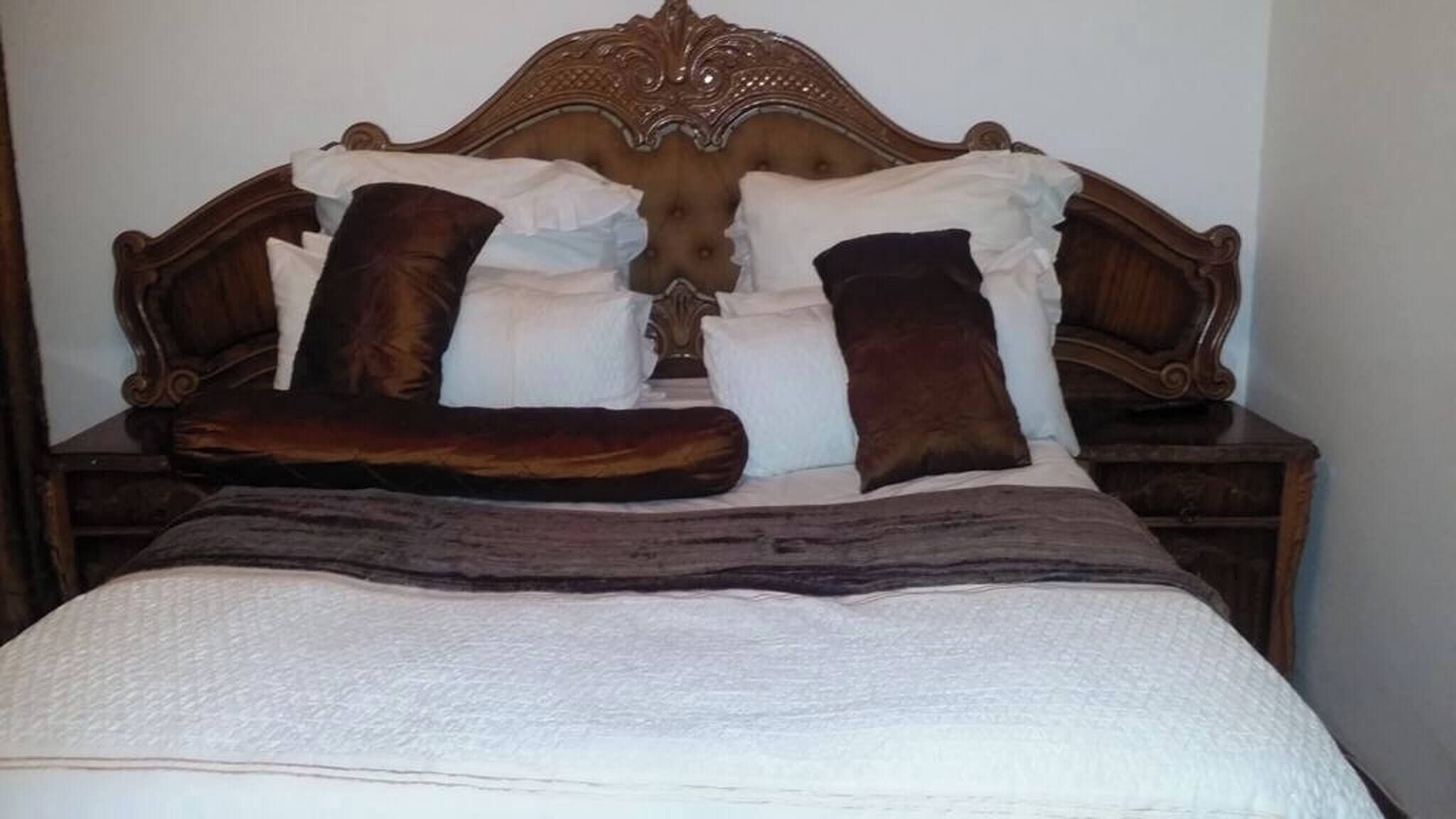 A bed with a tufted headboard, multiple pillows, and a blanket.