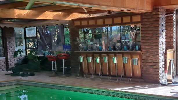 Ein Poolbereich mit freiem Blick auf den Pool, eine Bar mit Hockern und eine Backsteinmauer.