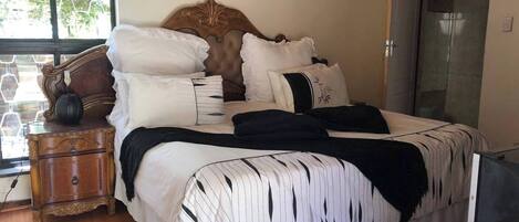 A bedroom with a large bed, a wooden nightstand, a dresser, and a wardrobe.