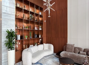 A modern living room with a sectional sofa, a wooden bookshelf, and a decorative ceiling light. - Westview Garden Spacious Balcony Room (Dubai)