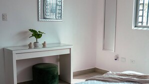 Una camera da letto con un letto, una scrivania, uno specchio, una finestra e una pianta.