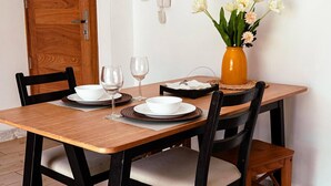 Un tavolo da pranzo con sedie, un vaso con fiori, un telefono e quadri appesi al muro.