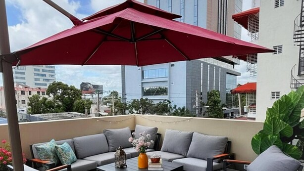 Una terrazza sul tetto con arredi da esterno, un ombrellone rosso e vista sulla città.